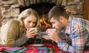 Romantic couple drinking tea in front of lit fireplace